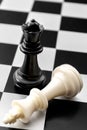 Checkmate, gender issues and fall of powerful leader concept with fallen white king and standing black queen on chess board Royalty Free Stock Photo