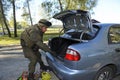 At the checkpoint, training. Soldier searching personal belongings of suspect in front of a stopped car