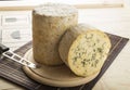 Cheddar PDO cheese with herbs cut and served on a wooden plate