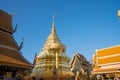 Chedi between rooftops with Buddhist architectural detail under blue sky Royalty Free Stock Photo