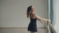 Cheeful adult woman professional ballerina is doing exercises at ballet bar stading on tiptoes, raising leg, doing