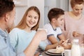 Cheeful girl enjoying dinner with her family