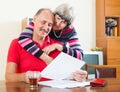 Cheeful mature man with wife reading documents