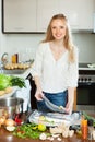 Cheeful woman cooking fish with lemon in sheet pan