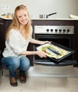 Cheeful woman cooking fish in oven