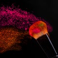 Cheek brush with neon cosmetic powder colorful spray on black background Royalty Free Stock Photo