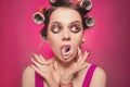 Cheeky girl with bubble gum posing on pink background in body, with curlers on head. Pretty woman with sweet makeup making