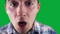 cheeky guy in a shirt twitches at the camera on the background of a green screen