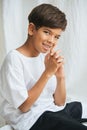 Cheeky indian boy sitting on a table, looking at the camera