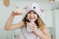 Cheeky little girl wrapped in a bear hooded towel, eating yogurt from a cup Royalty Free Stock Photo