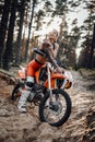 Female racer wearing motocross outfit with semi naked torso sitting on her bike in the forest Royalty Free Stock Photo
