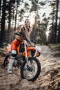 Female racer wearing motocross outfit with semi naked torso sitting on her bike in the forest Royalty Free Stock Photo