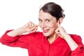 Cheeky young woman smiling in plugging fingers in ears Royalty Free Stock Photo