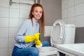 Cheereful redhaired ginger woman washing in rest room toilet wearing gloves