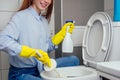 Cheereful redhaired ginger woman washing in rest room toilet wearing gloves