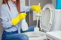 Cheereful redhaired ginger woman washing in rest room toilet wearing gloves