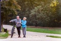 Cheerful active senior couple with bicycle walking in the park