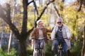 Cheerful active senior couple riding bicycles in public park together having fun. Perfect activities for elderly people. Royalty Free Stock Photo