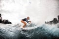 Cheerful woman in wetsuit engaged in extreme sport and rides board on river wave