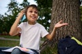 Cheerful adorable school child boy talking on mobile phone, cute smiling looking away, gesturing with hands, resting on the public Royalty Free Stock Photo