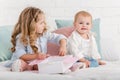 cheerful adorable sisters playing on bed