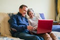 Cheerful adult couple sitting on a couch and watching a program on a laptop. selective focus
