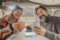 Cheerful adult couple smile and enjoy travel camper van holiday vacation together clinking with cups inside. Happy people tourist