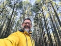 Cheerful adult happy man taking selfie picture in the woods enjoying outdoors leisure activity in national forestal park alone. Royalty Free Stock Photo