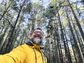 Cheerful adult happy man taking selfie picture in the woods enjoying outdoors leisure activity in national forestal park alone. Royalty Free Stock Photo