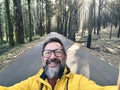 Cheerful adult happy man taking selfie picture in the woods enjoying outdoors leisure activity in national forestal park alone. Royalty Free Stock Photo