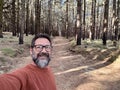 Cheerful adult happy man taking selfie picture in the woods enjoying outdoors leisure activity in national forestal park alone. Royalty Free Stock Photo