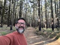 Cheerful adult happy man taking selfie picture in the woods enjoying outdoors leisure activity in national forestal park alone. Royalty Free Stock Photo