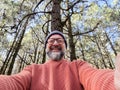 Cheerful adult happy man taking selfie picture in the woods enjoying outdoors leisure activity in national forestal park alone. Royalty Free Stock Photo