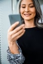 Mirthful smartphone user standing and smiling stock photo