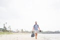 Cheerful adult man with bag having fun on tropical beach