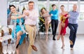 Cheerful man dancing jive with young brunette during corporate Christmas party