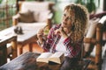 Cheerful adult pretty woman enjoy reading book at home sitting on the table. Attractive female people in wooden living room with Royalty Free Stock Photo