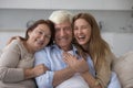 Cheerful adult woman hugging older senior parents