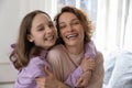 Cheerful affectionate teenage daughter hugging young mom looking at camera