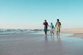 Cheerful african american boy holding father and mother's hands and running in sea against sky Royalty Free Stock Photo