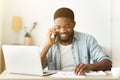 Cheerful african american businessman talking on phone and reading documentation Royalty Free Stock Photo