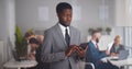 Cheerful african-american businessman using tablet computer standing in modern office Royalty Free Stock Photo