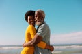 Cheerful african american couple embracing and looking away while standing against sea and blue sky Royalty Free Stock Photo