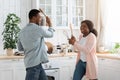 Cheerful black couple fighting with kitchenware, playing with utensils tools in kitchen Royalty Free Stock Photo