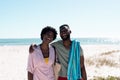 Cheerful african american couple laughing while standing at beach against sea and clear sky Royalty Free Stock Photo