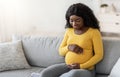 Cheerful african american expecting lady resting in living room