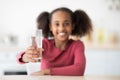 Cheerful african american girl teenager holding glass of water Royalty Free Stock Photo