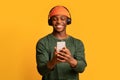 Cheerful African American Guy Using Smartphone And Listening Music With Wireless Headphones Royalty Free Stock Photo