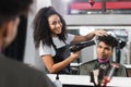 Cheerful african american hairstylist drying hair