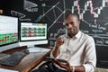 Joy of earning money. Cheerful african american male trader sitting by desk, pointing at camera and studying analytical Royalty Free Stock Photo